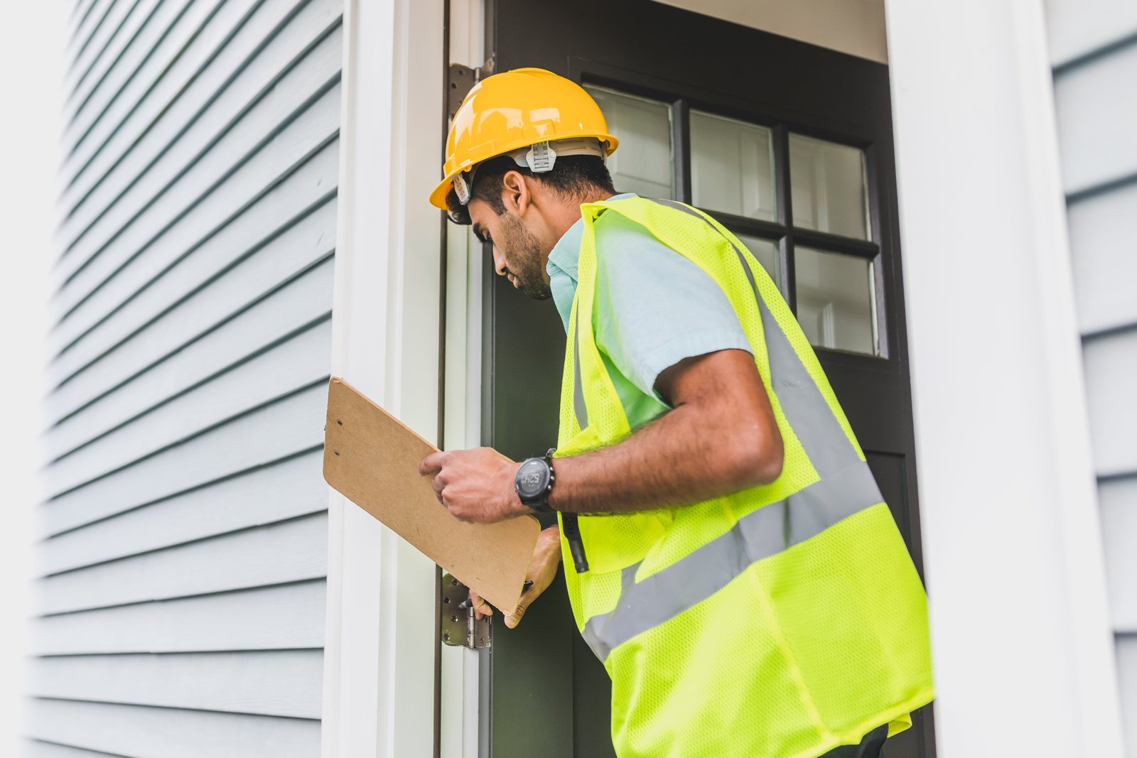 man in yellow hard hat and vest inspecting door