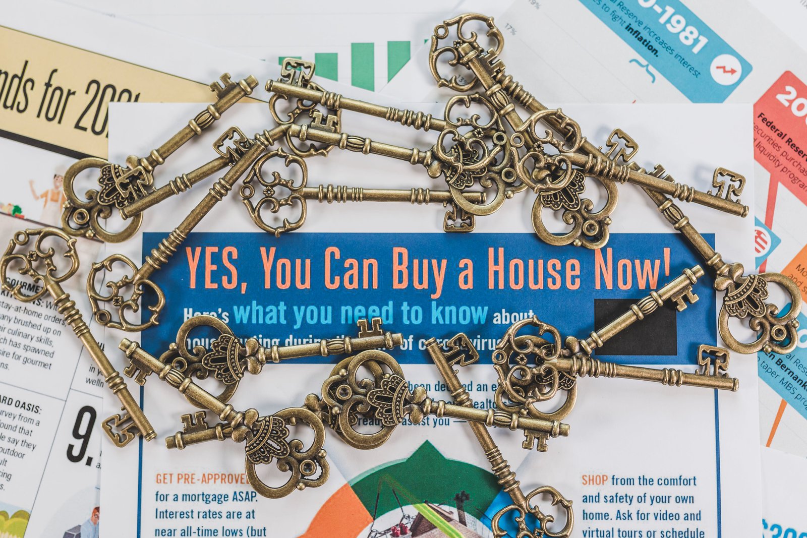 Old style brass keys scattered around marketing materials that say "Yes, You Can Buy a House Now!"